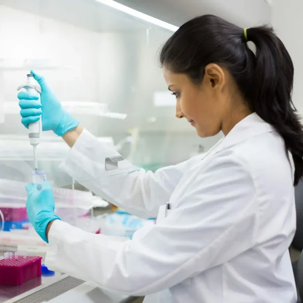 Closeup portrait, scientist pipetting from 50 mL conical tube with blue liquid solution, performing laboratory experiments, isolated lab . Forensics, genetics, microbiology, biochemistry